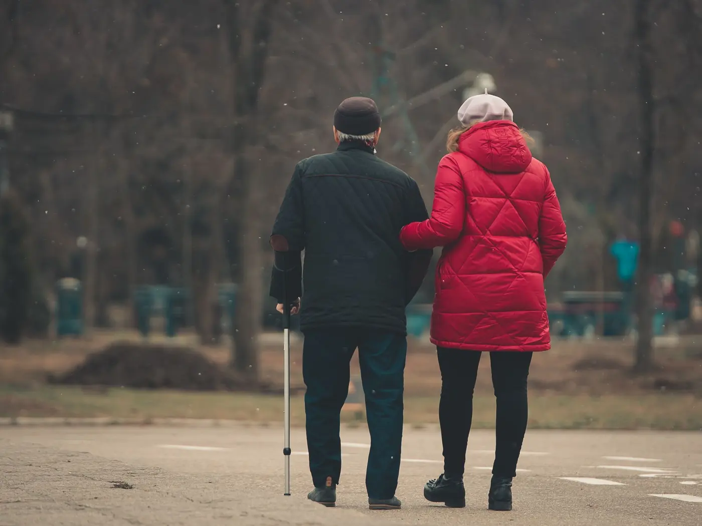 A carer walking arm in arm with an older man using a walking stick