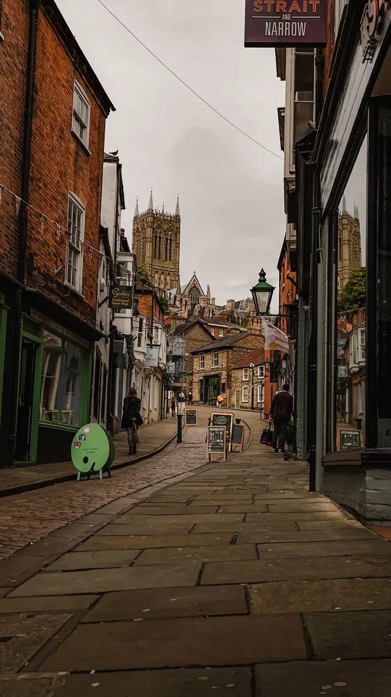 A cobbled street of old shops leading up to Lincoln Cathedral
