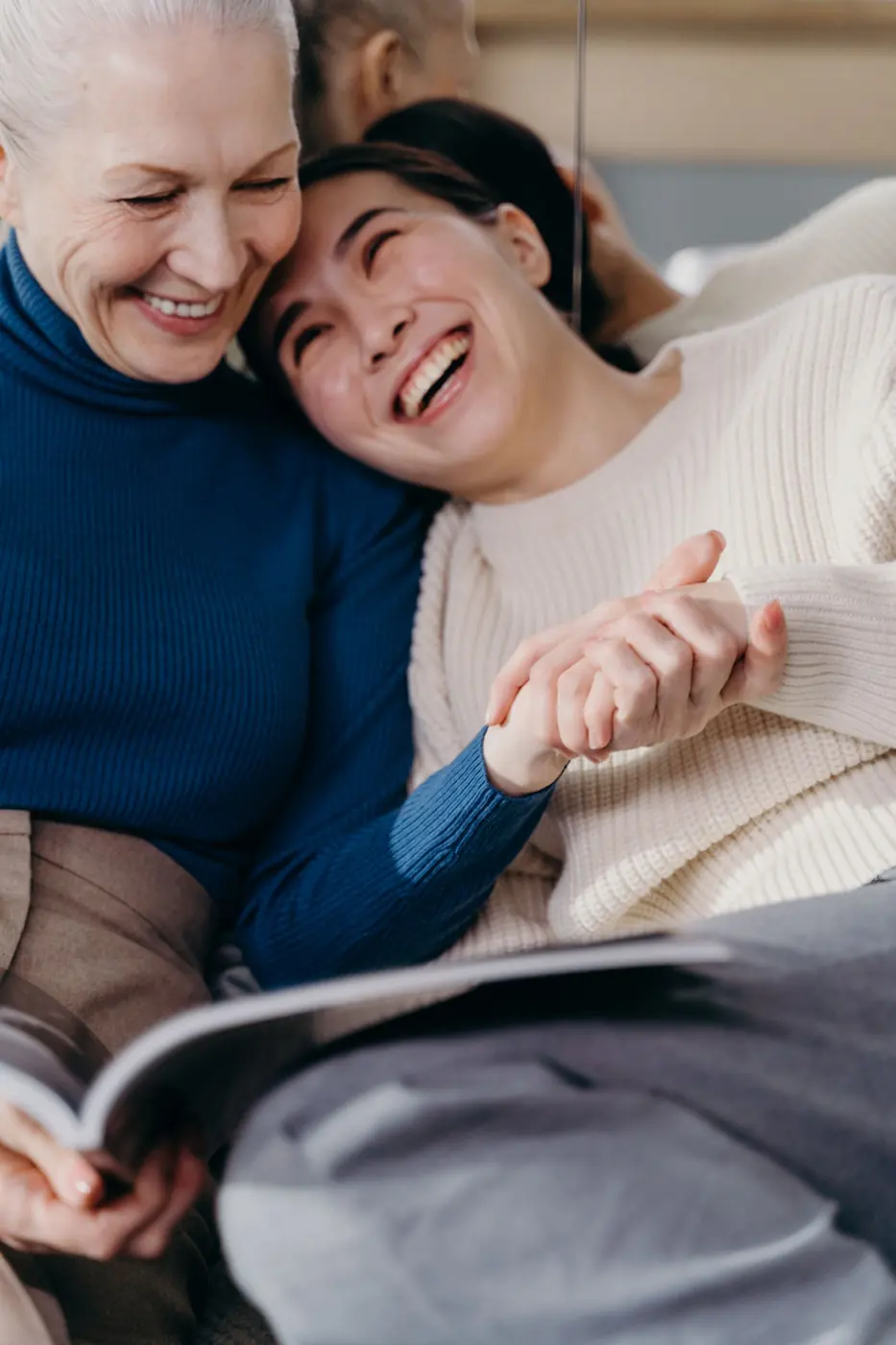 An older woman and a carer laughing together over a book
